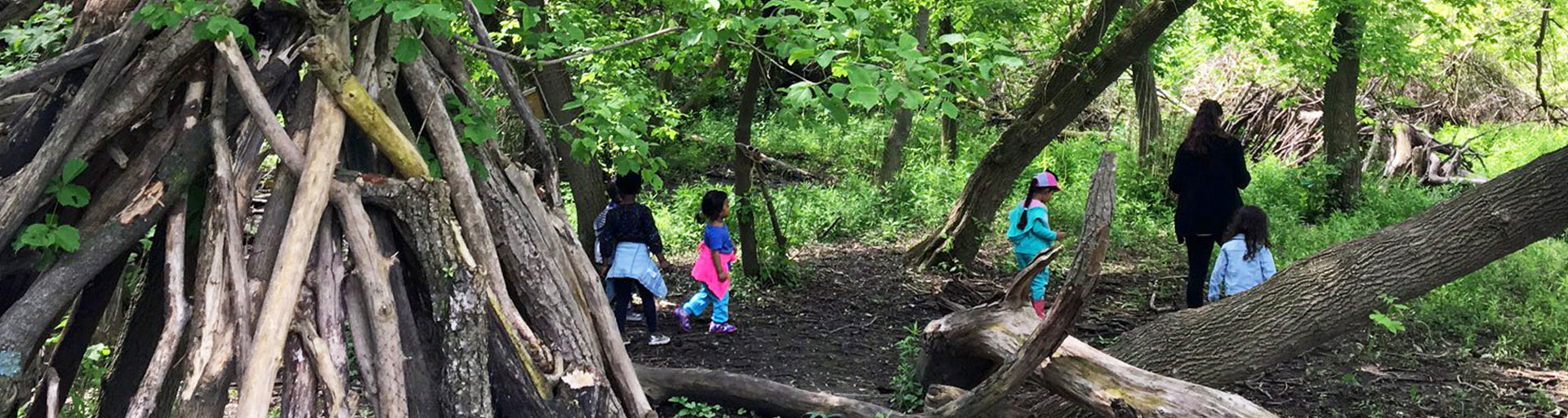 teacher and young children walking through forest