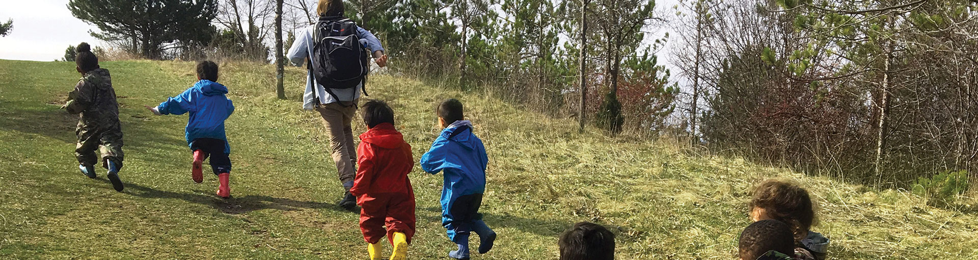 teacher and young children running up a hill