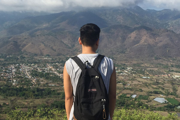 Person wearing backpack in front of hilly landscape
