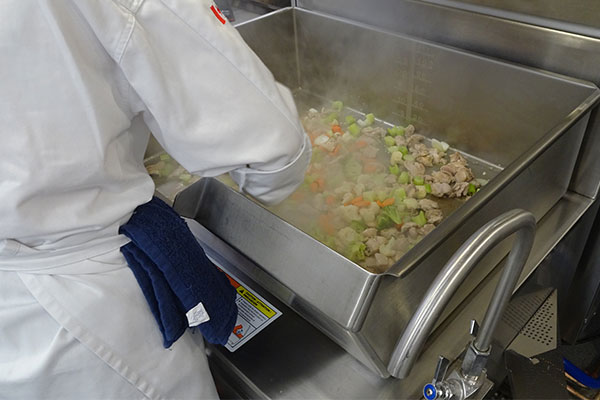 student cooking with a tilt fryer