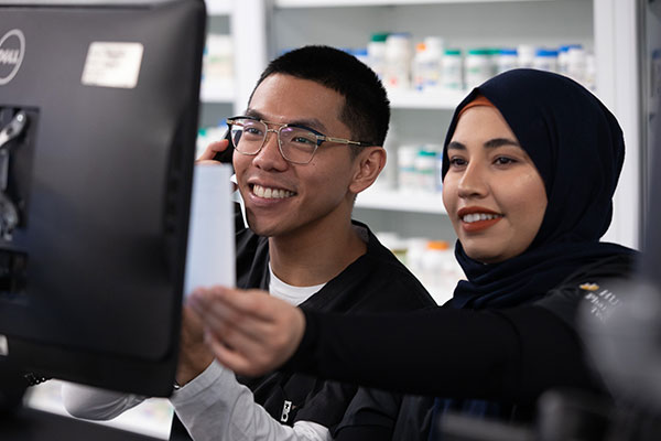 two people smiling looking at computer in pharmacy 