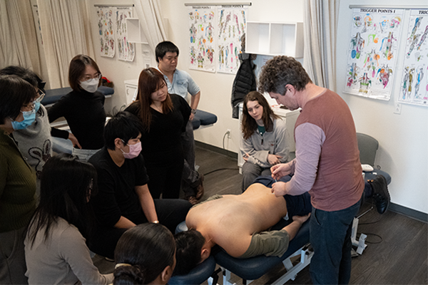 large group of students watching a teacher perform acupuncture