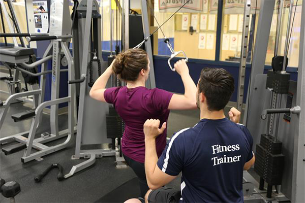 male fitness trainer helping a female