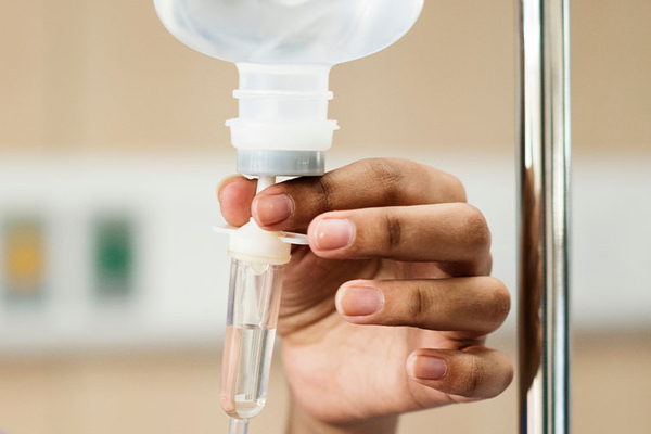 hand inserting tube into IV bottle