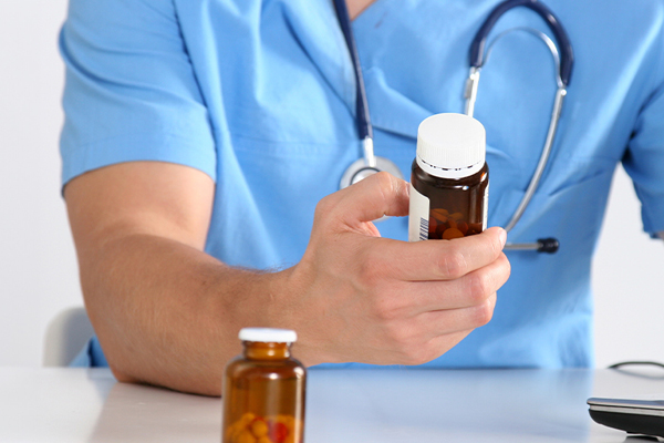 male nurse looking at a bottle of pills