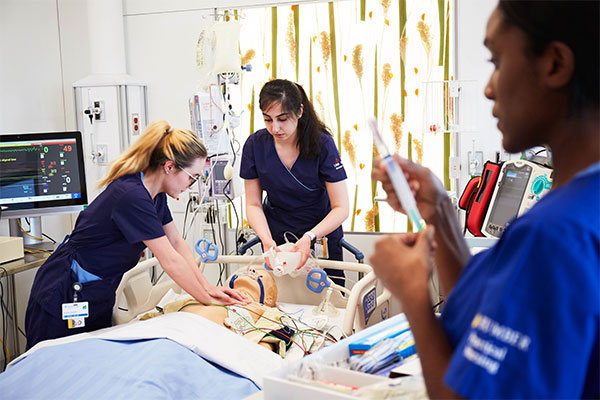 Three nursing students completing simulation on practice dummy