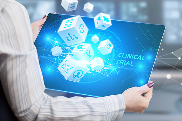 computer screen with the words clinical trial and cubes coming out of the screen with icons on them