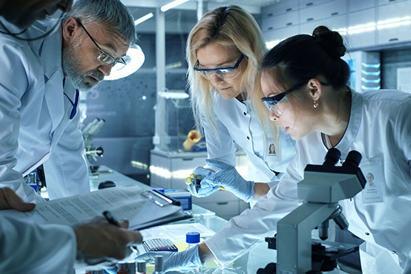 man and 2 women looking down at biomedical material