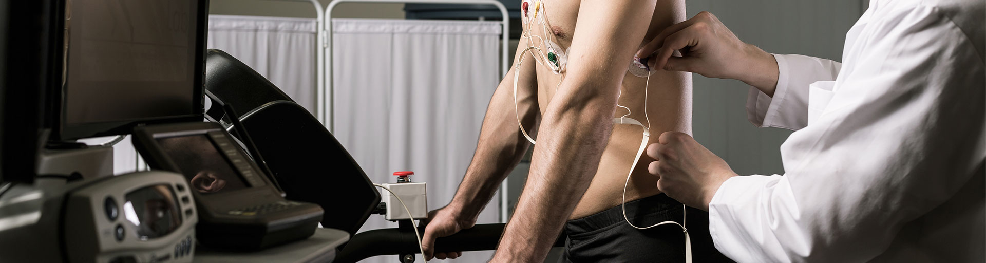 Person in a lab coat monitoring another person during a medical test