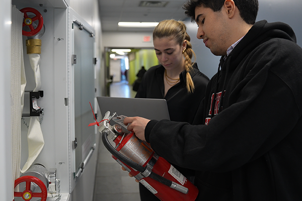 two students examining a fire extinguisher