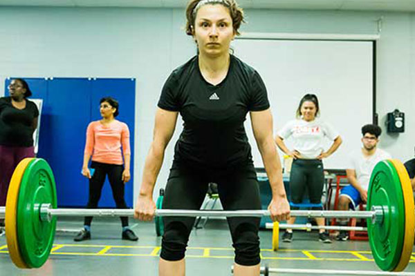 student lifting barbell with weights