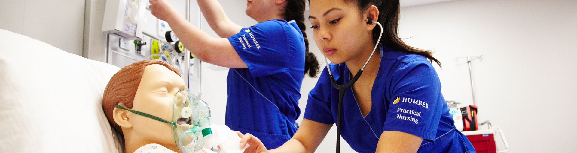 two practical nursing students checking a patient in the live lab
