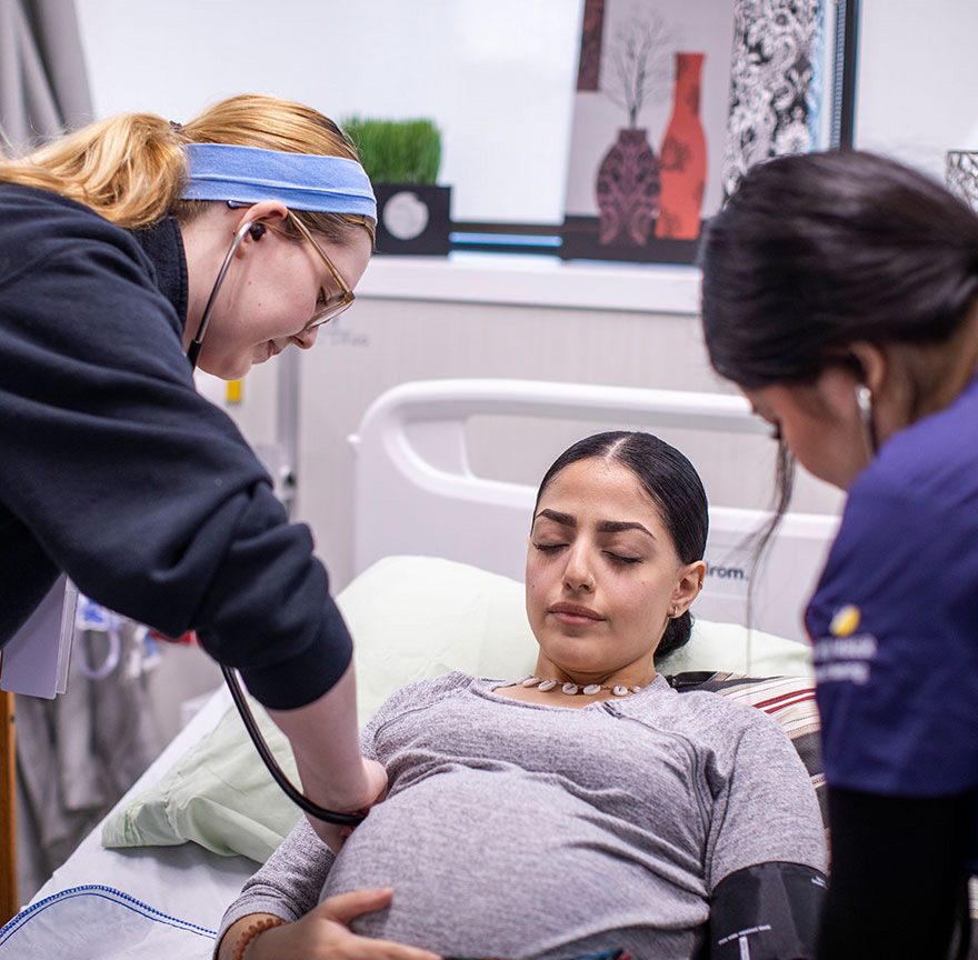 two nursing students performing CPR on a practice mannequin