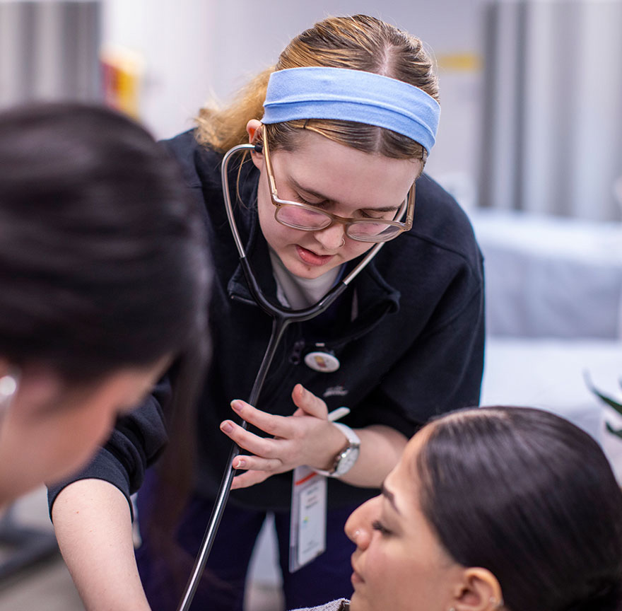 two nursing students performing CPR on a practice mannequin
